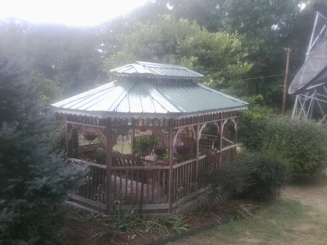 Green metal roof on a backyard gazebo surrounded by garden beds in Providence